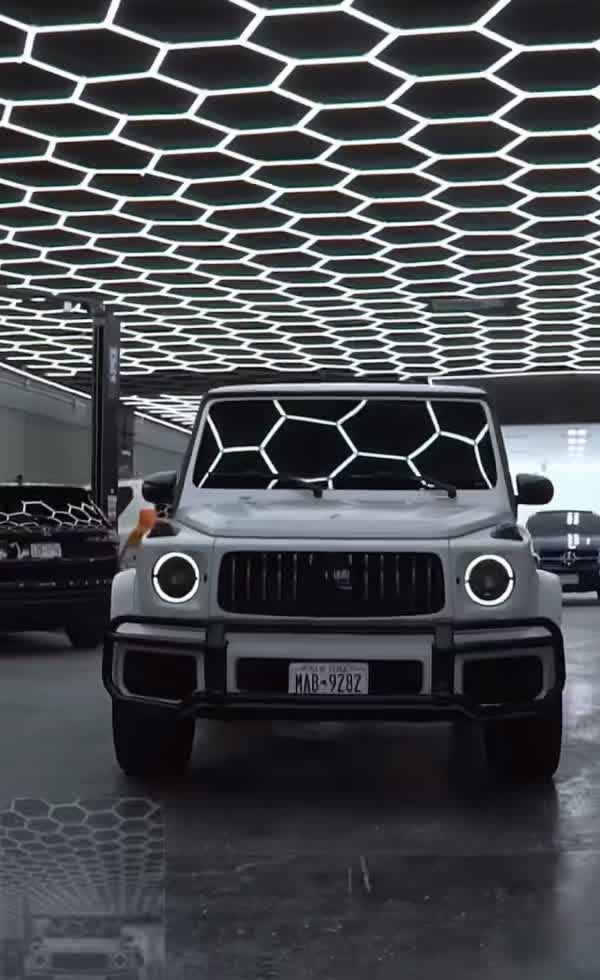 White Mercedes G-Wagon inside the ENY Automotive shop under hex-grid lights
